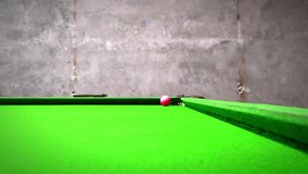 A red snooker ball resting on the green felt surface of a snooker table. Concrete wall background. 4K Video - Powered by Shutterstock - Get 15% off with code: PIKWIZARD15