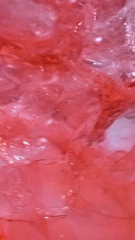 slow motion of ice cubes in cold red cocktail drink. beverage closeup, macro
