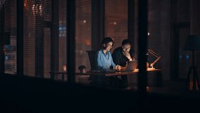 Hardworking businesspeople browsing laptop at dark office open space. Smiling businesswoman presenting online project to businessman at night. Happy colleagues working on company development overtime. - Powered by Shutterstock - Get 15% off with code: PIKWIZARD15