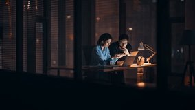 Overloaded partners brainstorming at night office looking laptop. Worried businesswoman massaging temples businessman explaining work problem. Two colleagues solving business issues overtime indoors. - Powered by Shutterstock - Get 15% off with code: PIKWIZARD15