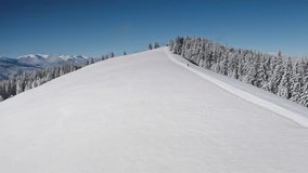 Aerial drone footage snowboarder climbing a pristine, snow-covered mountain ridge, tranquil forest and breathtaking mountain range, clear blue sky. Bukovel ski resort. Winter nature travel background - Powered by Shutterstock - Get 15% off with code: PIKWIZARD15