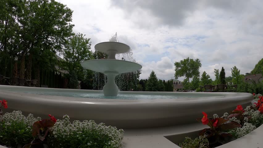 fountain - clear water gushes from a classic two-tier fountain, consisting of two round floors, under a cloudy sky
