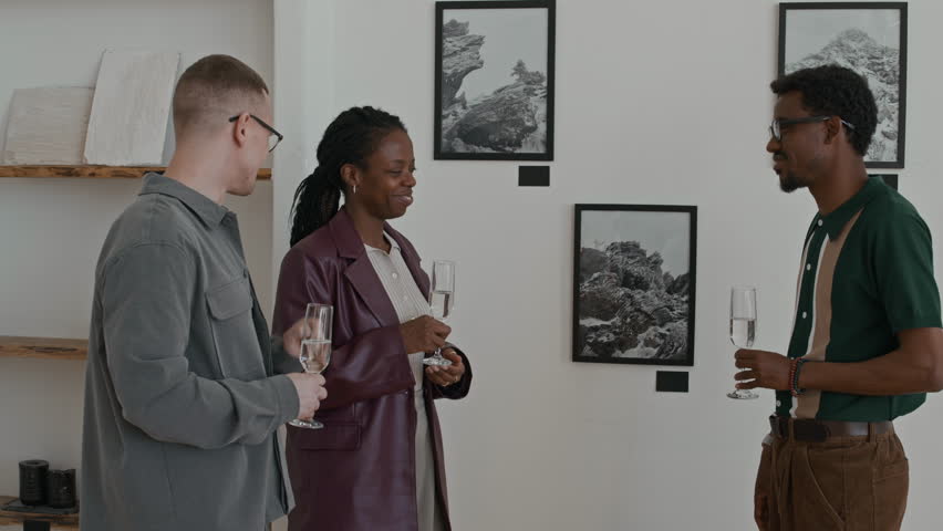 Diverse group of young people holding champagne glasses and communicating during modern art gallery opening copy space