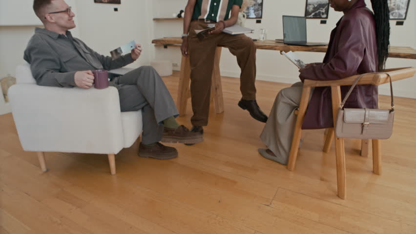 Zoom in shot of business meeting in modern art gallery with African American artist choosing prints for display