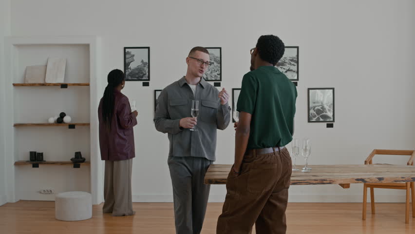 Group of young people holding champagne glasses and toasting during modern art gallery opening copy space