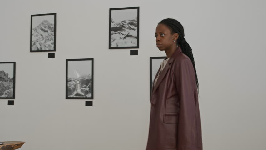 Shot of young African American woman meeting with artist in gallery and discussing photography print samples