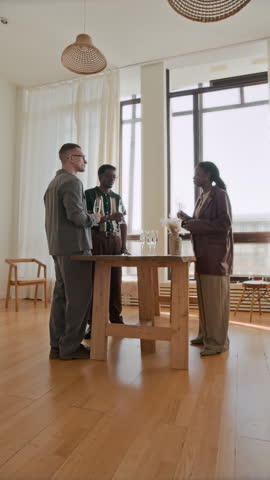 Vertical shot of diverse group of young people toasting with champagne glasses while celebrating art gallery opening full length