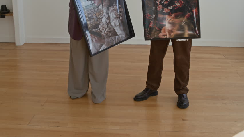 Pan up shot of modern art gallery with two people holding pictures and discussing new display