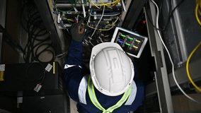 An expert repair technician in the office is connecting the server cabinet cables to ensure the system works properly according to standards. - Powered by Shutterstock - Get 15% off with code: PIKWIZARD15