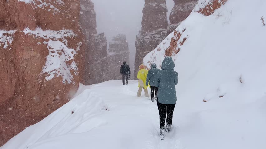 Adventurers trekking through snowy canyon with rocky cliffs in Bryce Canyon, USA