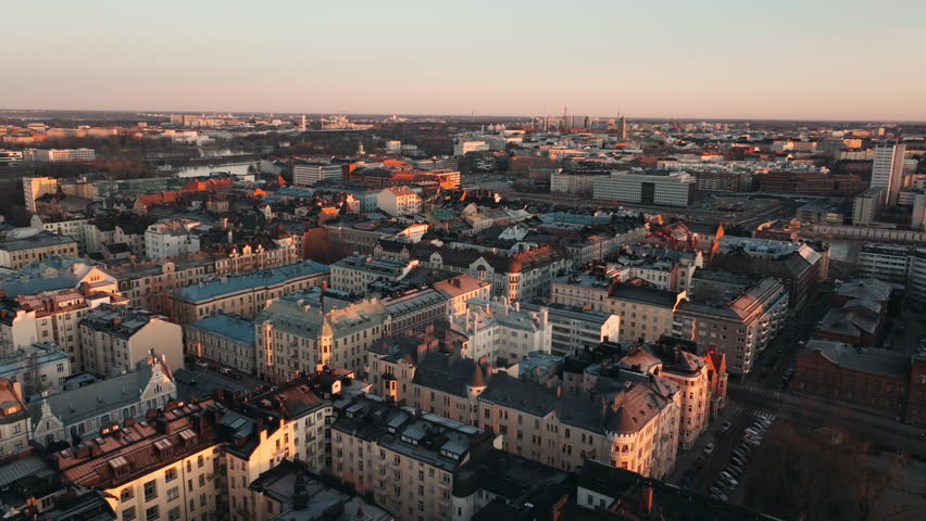 Aerial drone shot of the Helsinki Cathedral, Finland, at sunrise, with golden light illuminating the historic landmark and surrounding neoclassical architecture
