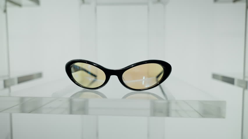A Stylish Pair of Black Sunglasses Displayed Elegantly in a Minimalist Showcase, Highlighting Their Unique Design and Fashion Statement