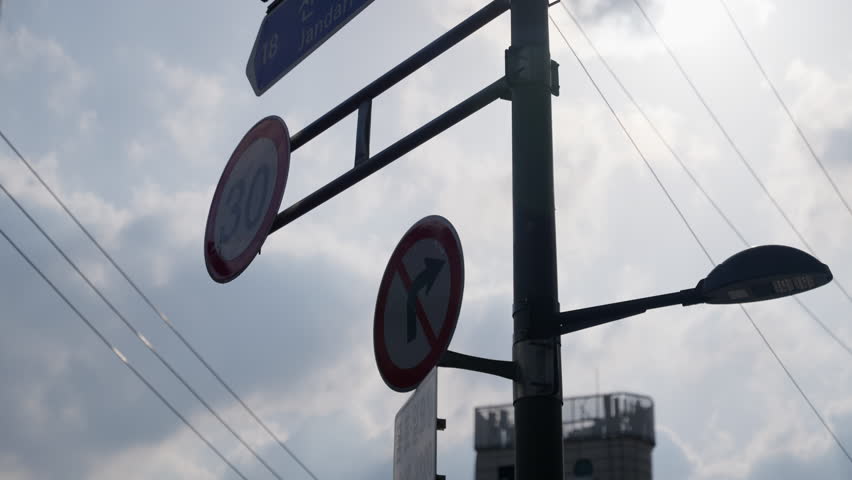 Traffic Signs Indicating Speed Limit and Prohibition on Right Turns Against a Cloudy Sky, Capturing Urban Infrastructure in a Dynamic City Environment