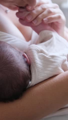 Loving mother breastfeeds her baby in a warm, cozy room full of comfort and tenderness. Vertical video