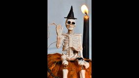 Decor skeleton in a black hat sits on a pumpkin. Vertical video.Halloween background - Powered by Shutterstock - Get 15% off with code: PIKWIZARD15