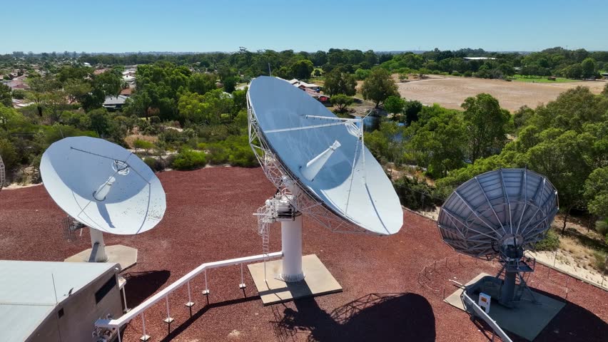 Closeup Of Satellite Dishes In Ground Station Surrounded By Green Trees. orbiting drone shot