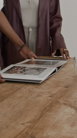 Vertical shot of young African American artist discussing sample prints in art gallery