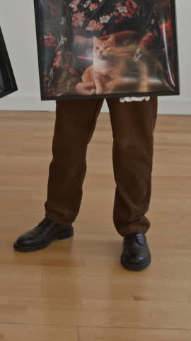 Vertical shot of modern art gallery with two people holding pictures and discussing new artwork