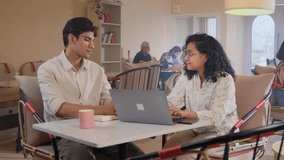 Two young, attractive, smiling corporate office colleagues or friends interacting and busy working together using a laptop in a cafe or coworking space. Business, relationship, collaboration concept. - Powered by Shutterstock - Get 15% off with code: PIKWIZARD15