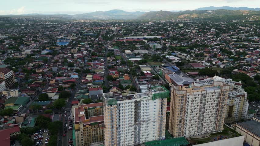Aerial view of crane atop building rooftop construction site with cityscape backdrop at Marikina City, Philippines.