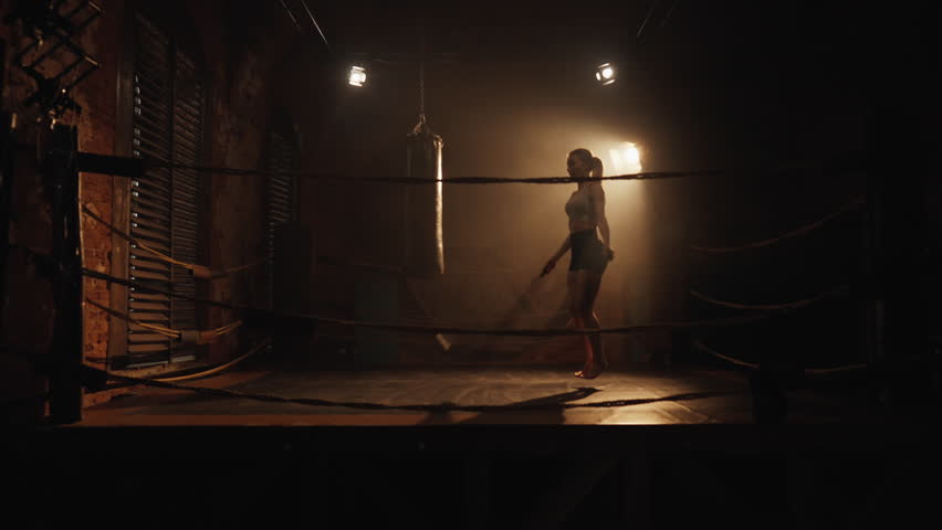 Sport and fitness, athletic woman training in night in boxing ring, jumping rope . Active pastime for stay healthy and slender, lose weight and keep fit, professional sportswoman developing endurance