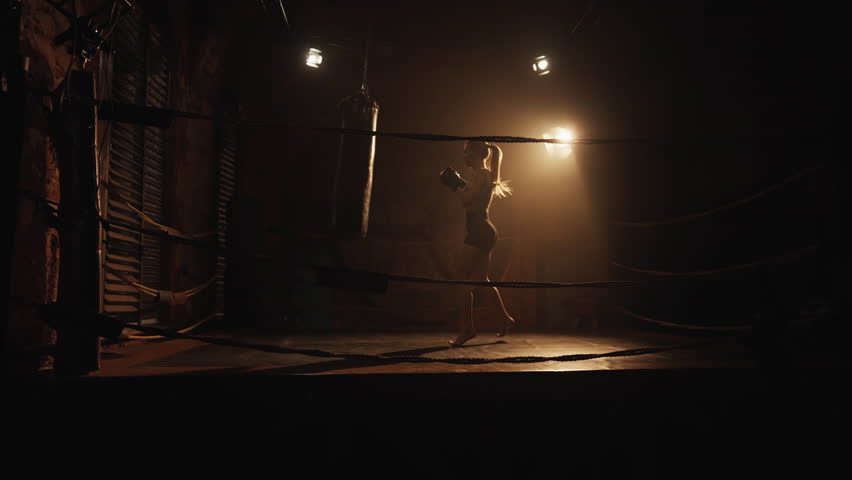 Sport and fitness, active hobby and self-defense, woman boxing with punch bag. Full-length shot on boxing ring, female silhouette moving, energy and power of women, fighting with fears, release stress