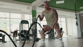 Muscular man engaging in an intense workout with battle ropes in a modern, well-equipped gym. Fitness, strength, and determination concept. - Powered by Shutterstock - Get 15% off with code: PIKWIZARD15