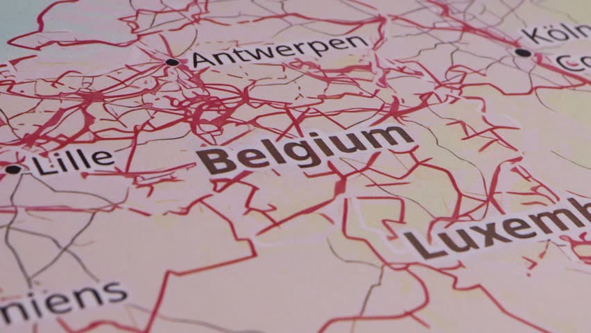 Close-up of a detailed map with a red pushpin precisely marking the location of Belgium as part of a travel destination
