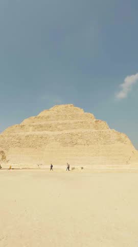 Tourists walking in the desert near the step pyramid of djoser, an archeological site in saqqara, egypt