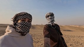Tourists wearing a keffiyeh take some selfies in the desert near the pyramids of giza in egypt - Powered by Shutterstock - Get 15% off with code: PIKWIZARD15