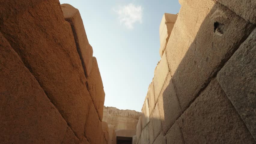 Sunlight streaming across red pyramid's massive stone walls, revealing intricate textures and ancient architectural grandeur of egyptian historical landmark