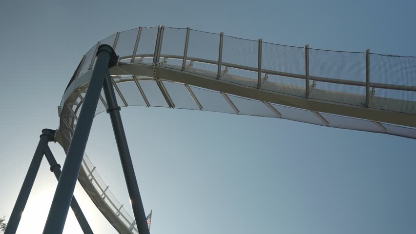 Thrill-seekers enjoy an exhilarating roller coaster ride at a marine amusement park. The excitement builds as the coaster climbs and plunges under the bright blue sky.