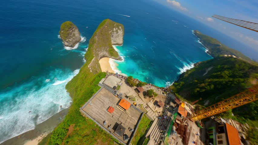 Cinematic FPV drone flight over dramatic cliffs, white sand beach, and turquoise ocean at iconic Kelingking Beach in Nusa Penida, Bali, Indonesia. Ideal for travel, summer, tropical adventure themes.