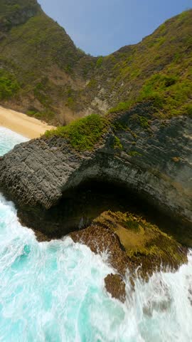 Cinematic FPV drone flight over white sand beach and turquoise ocean at iconic Kelingking Beach in Nusa Penida, Bali, Indonesia. Ideal for travel, summer, tropical adventure themes.