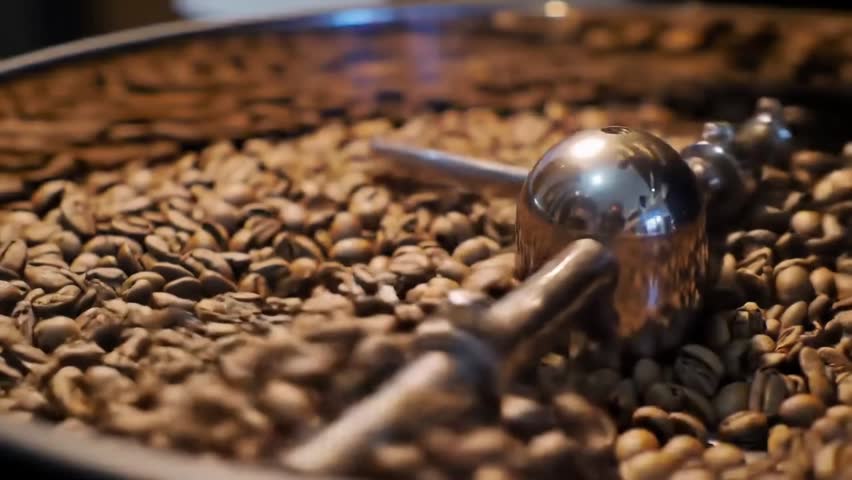 Freshly roasted coffee beans spinning inside a modern industrial roasting machine. A close-up view that captures the rich texture, aroma, and essence of quality coffee production