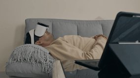 Relaxed man wearing VR headset while lounging on couch at home, immersive tech experience - Powered by Shutterstock - Get 15% off with code: PIKWIZARD15