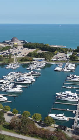 Aerial View of Marina by the Lake. A marina filled with boats and yachts, located near a scenic lakefront and park on a sunny day.