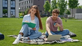College students studying on nature sharing ideas. Young man showing laptop screen to woman writing in copybook on blanket. Two freelancers collaborating on project sitting green grass urban park. - Powered by Shutterstock - Get 15% off with code: PIKWIZARD15