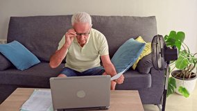 Video of Elderly man managing finances on a laptop while trying to stay cool using an electric fan - Powered by Shutterstock - Get 15% off with code: PIKWIZARD15