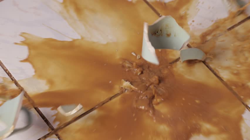 Cup of coffee breaking on the kitchen tile floor, bad luck in the morning dropping hot beverage, slow motion from 240 FPS footage