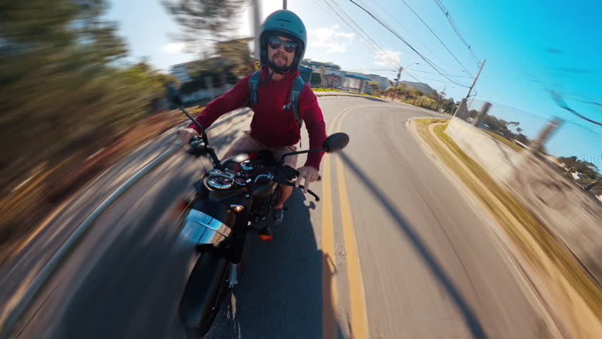 Man rides classic black motorcycle on the street of a town