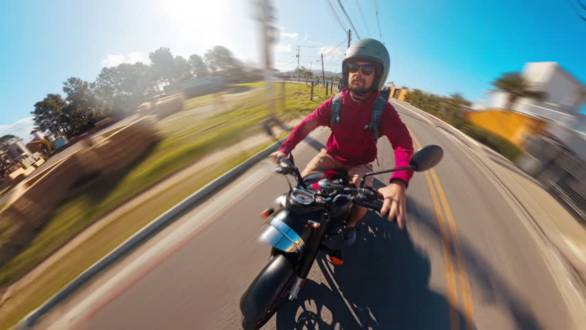 Man rides classic black motorcycle on the street of a town