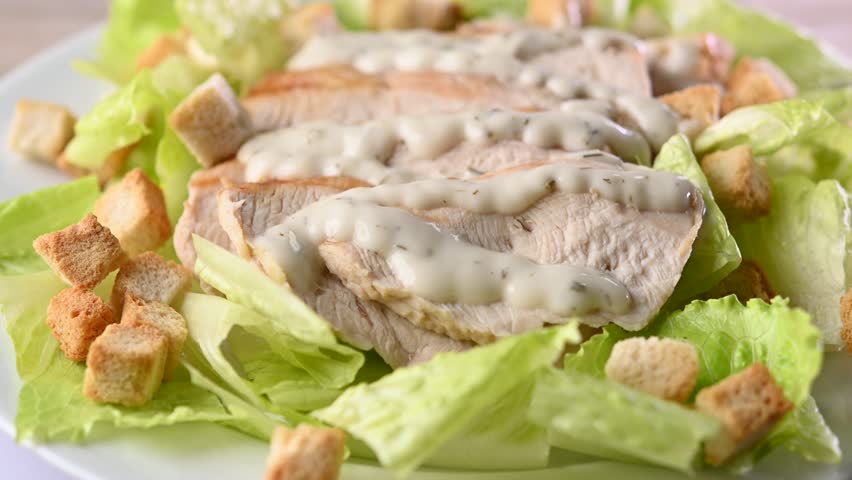 Rotating Classic Caesar Salad	with chicken on wooden table