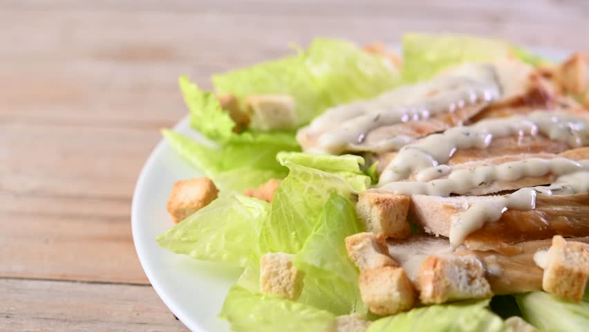 Rotating Classic Caesar Salad	with chicken on wooden table
