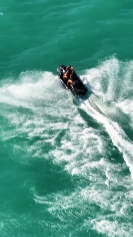 Fun day on the water with jet ski activity at the beach on a sunny afternoon in clear coastal waters. Vertical Video