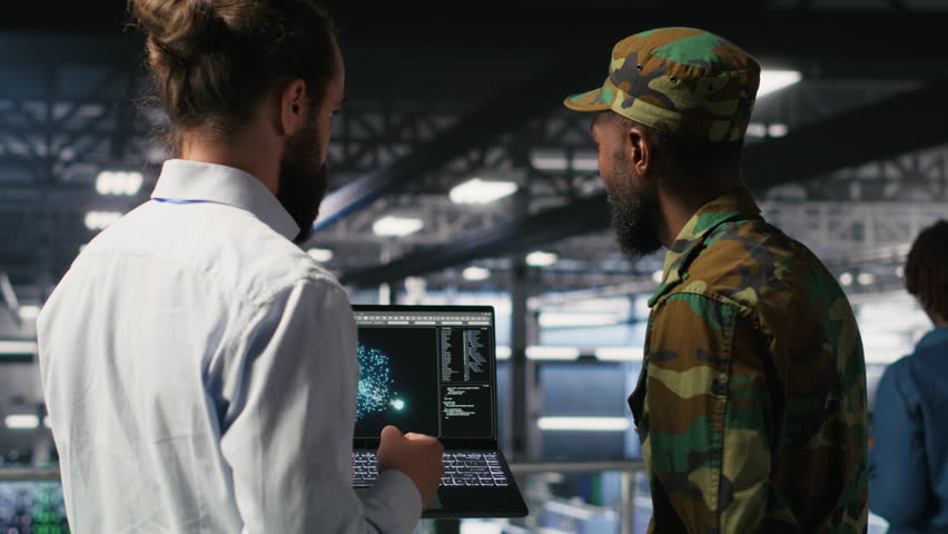 Military units overseeing AI computing operations on notebook in high tech server facility. Army tech experts using machine learning intelligence to oversee communication systems