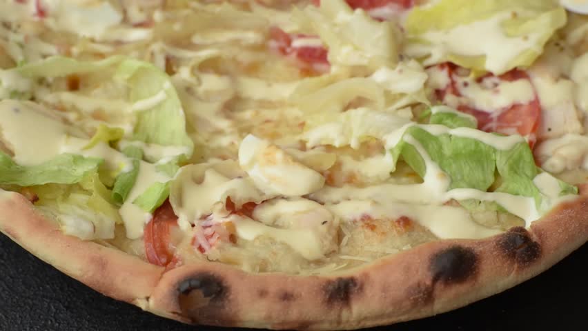 Italian caesar pizza with cheese and chicken, lettuce leaves and sauce. Fast food, sliced pizza