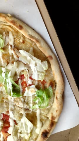 Italian caesar pizza with cheese and chicken, lettuce leaves and sauce. Fast food, sliced pizza
