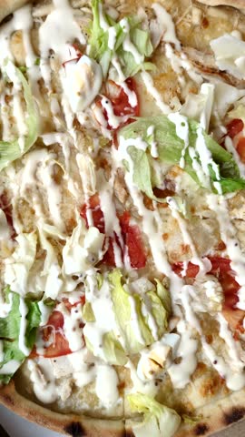 Italian caesar pizza with cheese and chicken, lettuce leaves and sauce. Fast food, sliced pizza