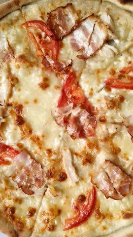 Italian pizza with chicken and bacon, cheese, tomatoes and sauce. Fast food, sliced pizza
